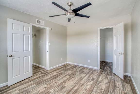 A room with a ceiling fan and wooden flooring.