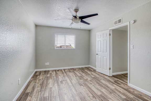 A room with a ceiling fan and a door leading to another room.