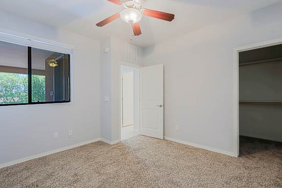 A room with a ceiling fan and carpeted floor.