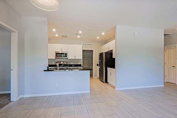 A kitchen with white cabinets and black appliances.