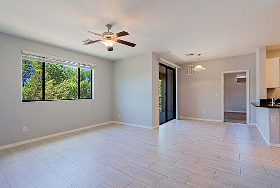 A spacious room with a ceiling fan and a large window.