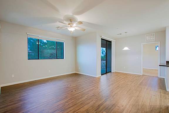 A room with a ceiling fan and wooden flooring.