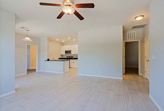 A spacious kitchen with white cabinets and a ceiling fan.