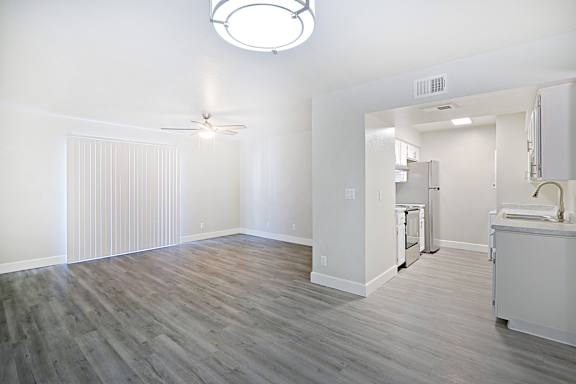 A room with a ceiling fan and a kitchenette.