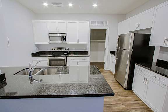 A kitchen with white cabinets and black countertops.