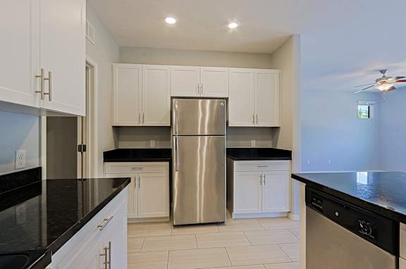 A kitchen with white cabinets and a stainless steel refrigerator.