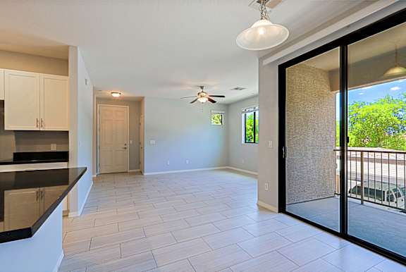 A spacious living room with a sliding glass door leading to a balcony.