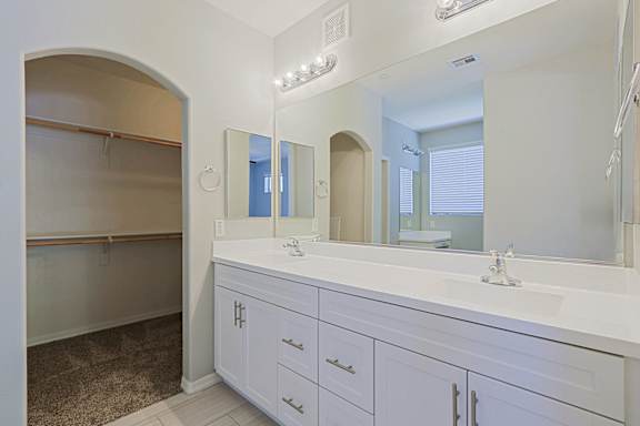 A bathroom with a white vanity and a large mirror.