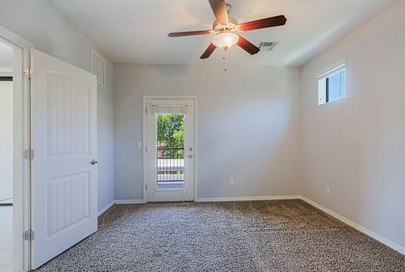 A room with a ceiling fan and carpeted floor.