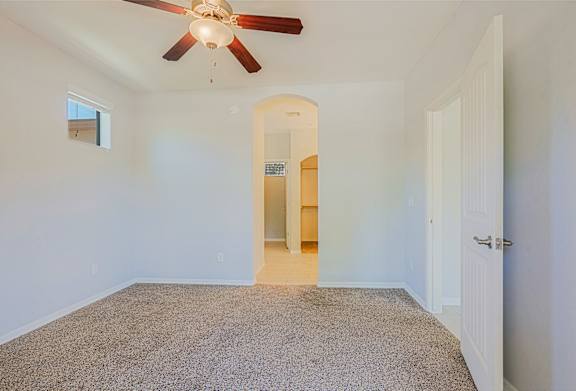 A room with a ceiling fan and carpeted floor.