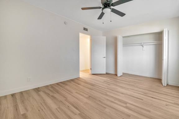 A room with a ceiling fan and light wood flooring.