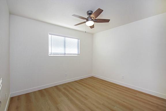A room with a ceiling fan and a window with blinds.