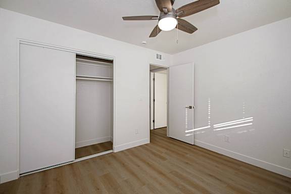 A room with a ceiling fan and a door on the right side.