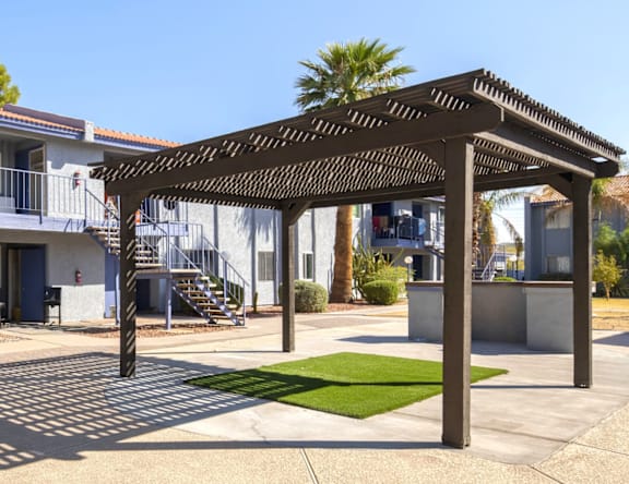 A patio with a pergola and a green lawn.