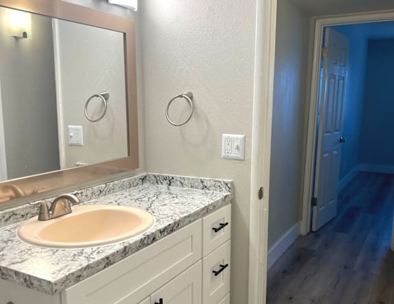 A bathroom with a marble countertop and a round mirror.
