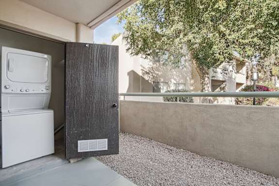 A black washing machine is in a small outdoor space.