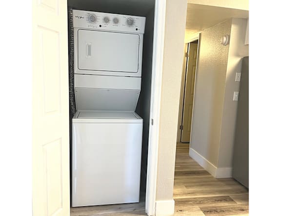 A white dishwasher is in a narrow space between a door and a wall.
