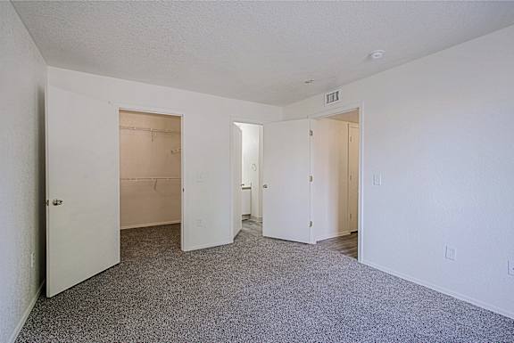 A large empty room with carpeted floor and white walls.