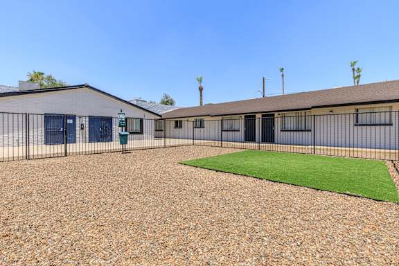 A building with a gravel yard in front and a small green area.