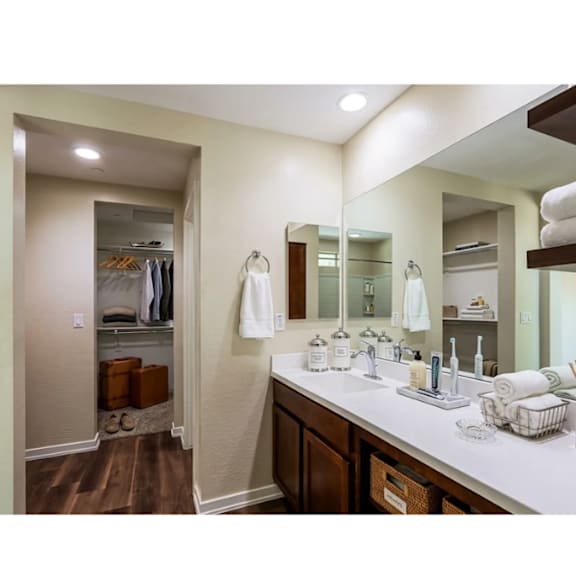 A bathroom with a white counter top and brown cabinets.