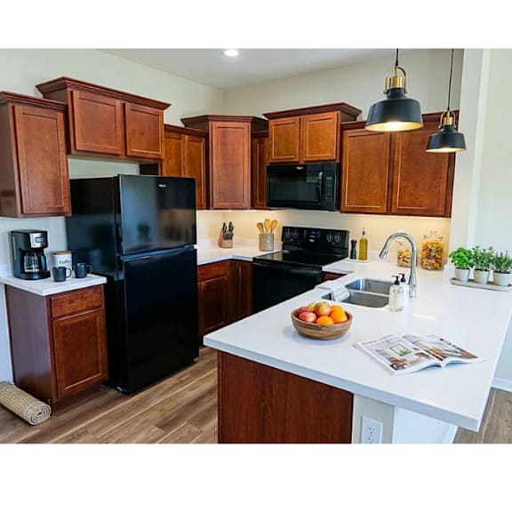 A kitchen with black appliances and wooden cabinets.