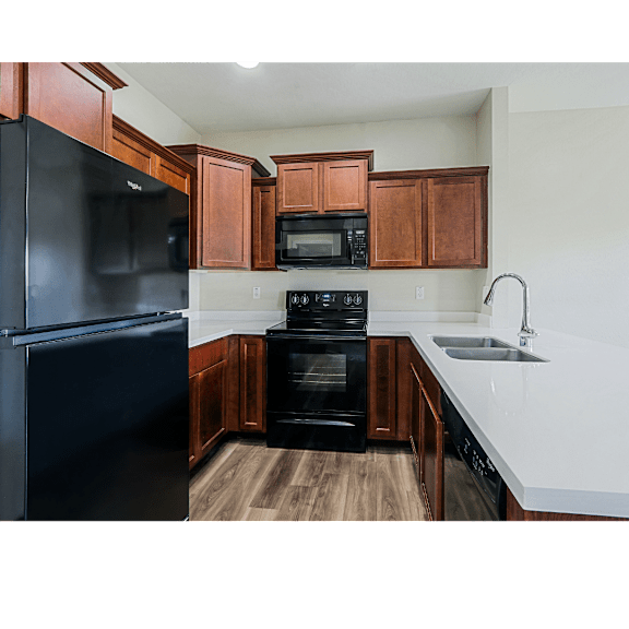 A kitchen with a black refrigerator and wooden cabinets.