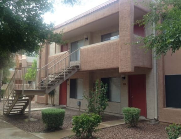 A building with a red door and a staircase leading to the second floor.