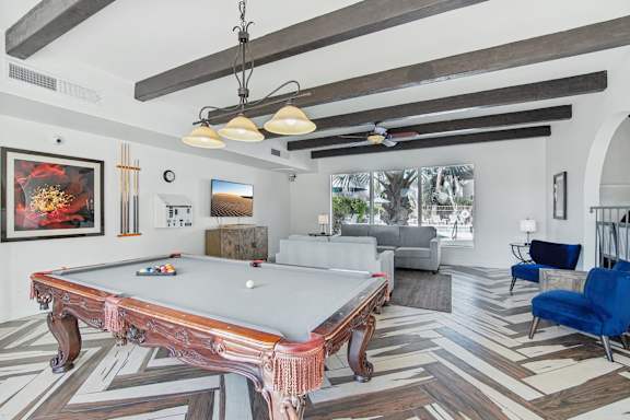 A pool table is in the middle of a room with a blue chair to the right. at The Viridian Apartments, Scottsdale