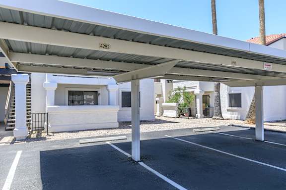 A parking lot with a white building and a palm tree in the background.