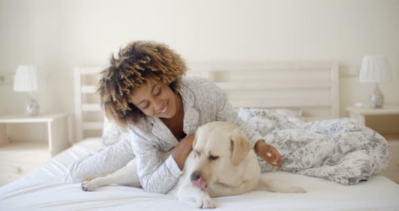 a woman laying in bed with her dog