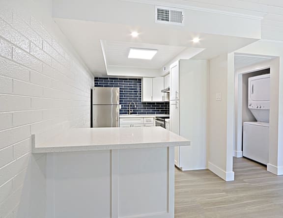 A kitchen with a white countertop and a refrigerator.