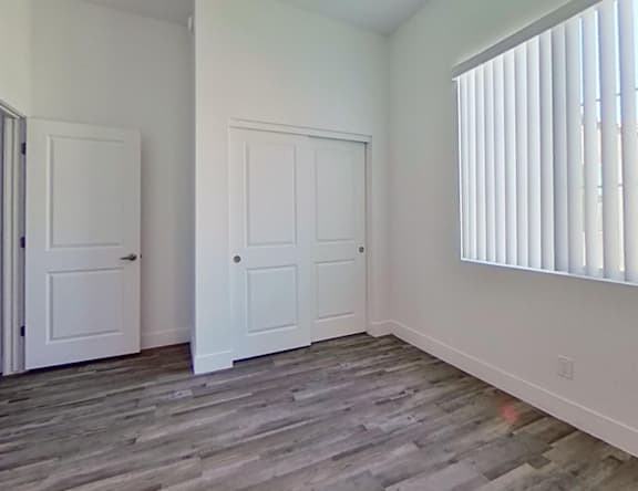 A room with two doors and a window with blinds.