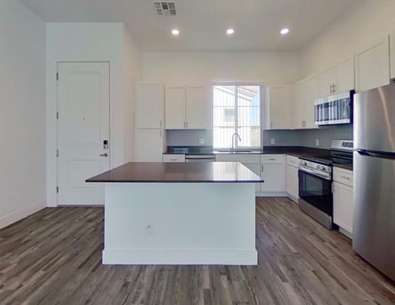 A kitchen with a white island and stainless steel appliances.