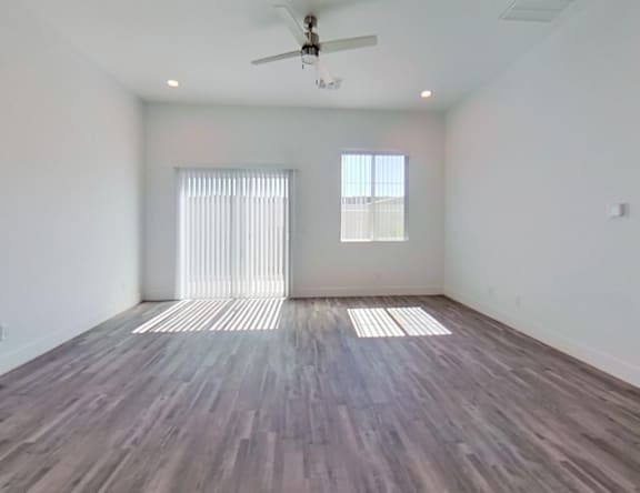 A room with a ceiling fan and two windows with blinds.