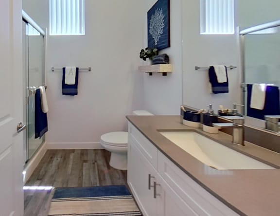 A bathroom with a toilet, sink, and mirror.
