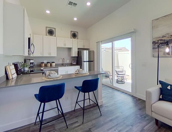 A kitchen with blue chairs and a white counter.