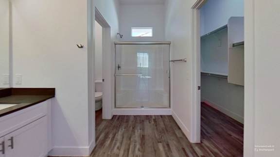 A bathroom with a glass shower door and wooden floors.