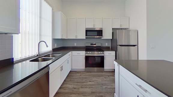 A modern kitchen with white cabinets and stainless steel appliances.