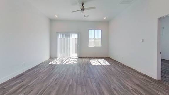 A room with a ceiling fan and wooden flooring.