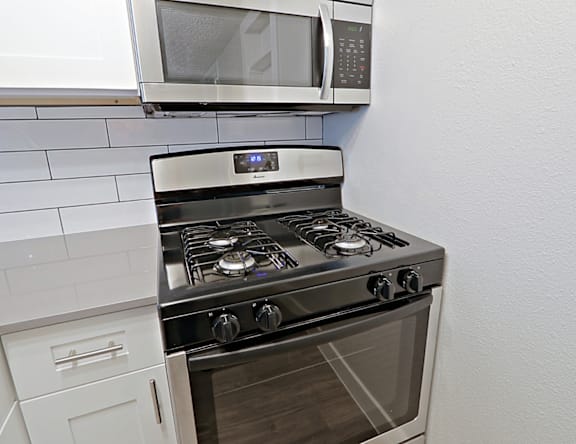 A modern kitchen with a stove and microwave above it.
