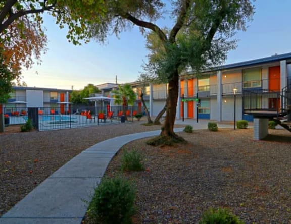 A tree stands in front of a building with orange trim.