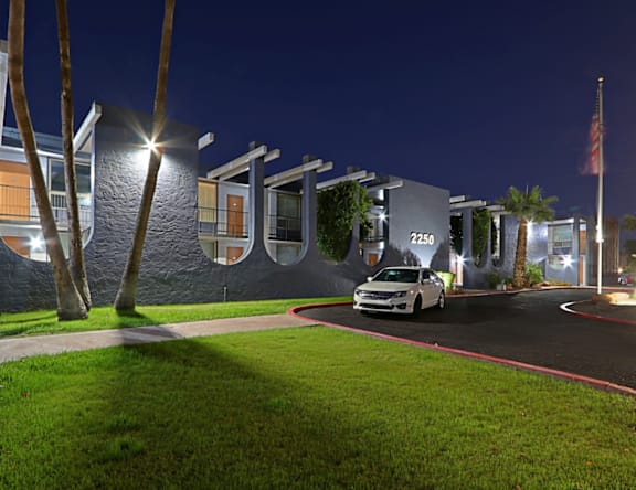 A white car is parked in front of a building with the number 2250 on it.