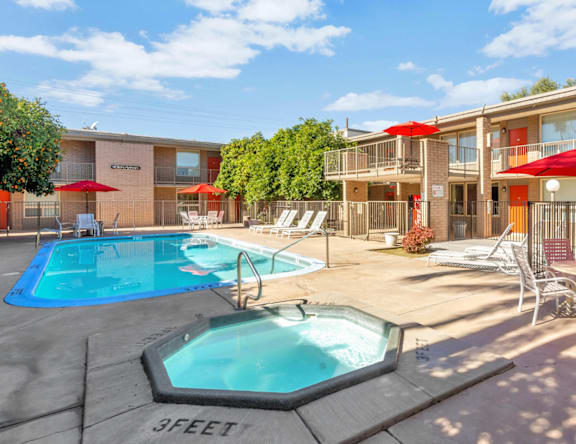 A pool with a hot tub and chairs in front of a building.