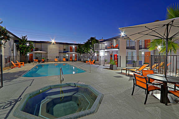 A swimming pool area with orange chairs and a table.