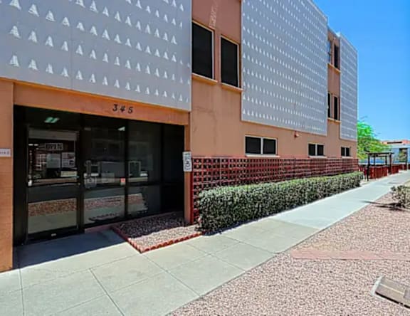 A building with a brown facade and a white patterned wall.