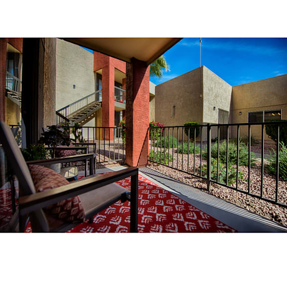 A balcony with a red carpet and a metal railing.