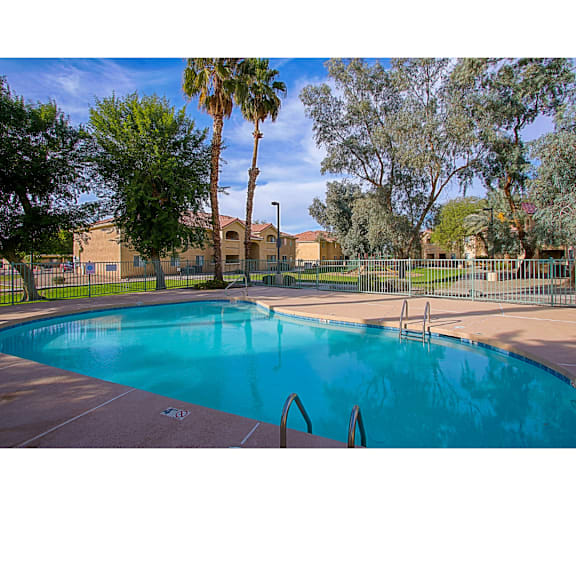 A swimming pool surrounded by a fence and trees.