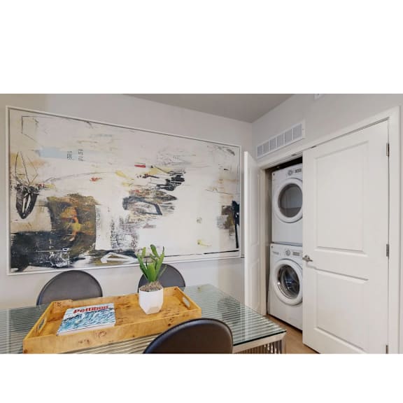 A dining room with a table and chairs and a large abstract painting on the wall.