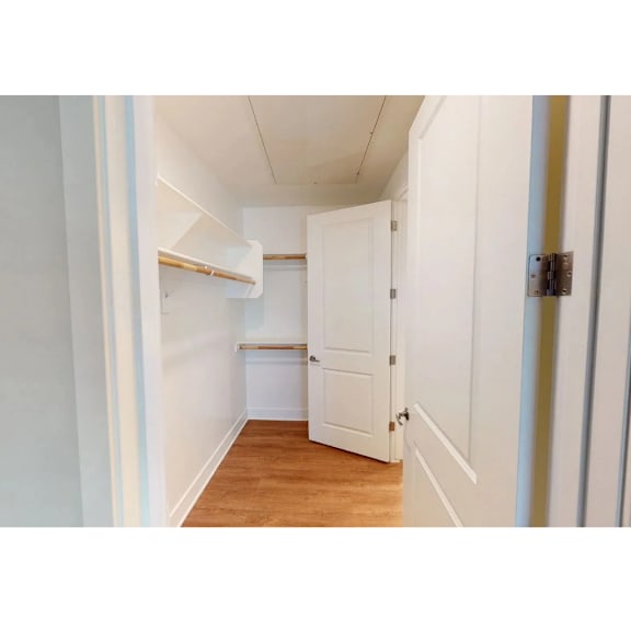 A white door is in a hallway with a wooden floor.