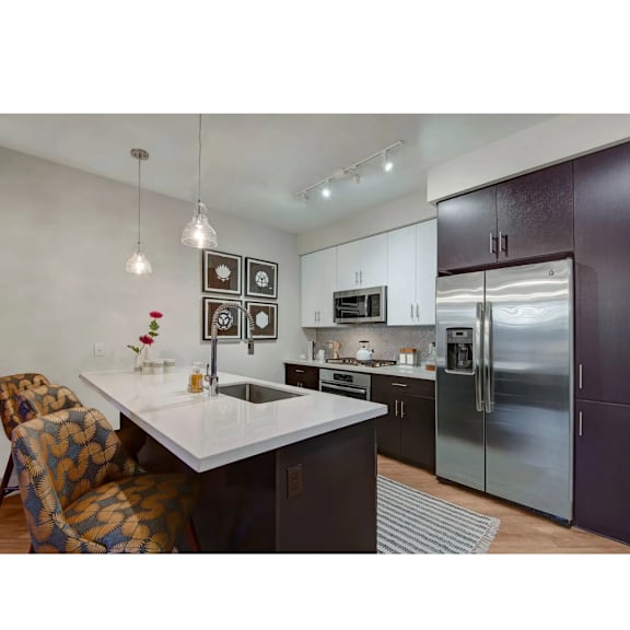 A modern kitchen with a white countertop and a refrigerator.